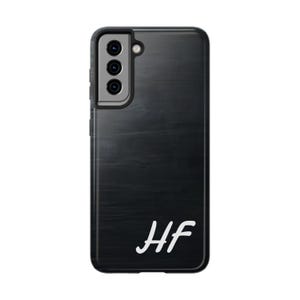 Könnte beinhalten: Schwarze Handyhülle mit Holzmaserung und den Initialen "HF" in weißer Schrift.