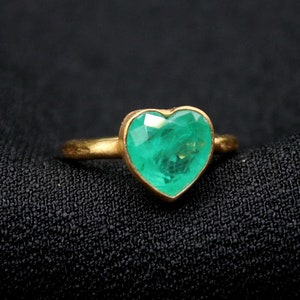 May include: A gold ring with a heart-shaped emerald green gemstone.