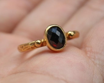 May include: A gold ring with a black oval gemstone and small gold accents on the band.