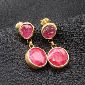 May include: A pair of gold earrings with two pink gemstones on each earring.
