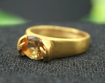 May include: A gold ring with a large, round, light brown gemstone.