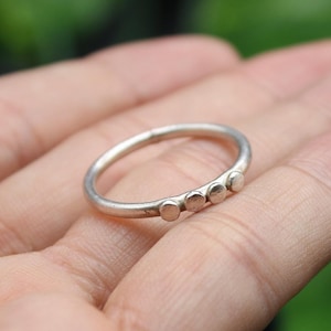 May include: A silver ring with four small round accents.