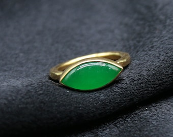 May include: A gold ring with a green gemstone in the shape of a leaf.