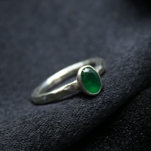 May include: A silver ring with a green oval gemstone set in the center.