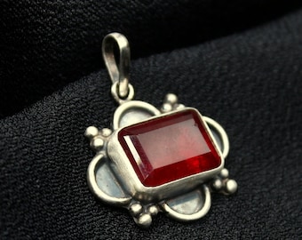 May include: A silver pendant featuring a red gemstone set within an ornate frame.