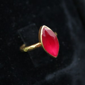 May include: A gold ring with a bright pink marquise-shaped gemstone.