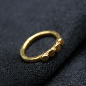 May include: A gold ring with five small round bumps on the band.