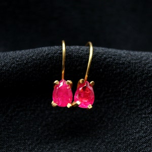 May include: A pair of gold earrings with teardrop-shaped ruby stones.