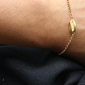 May include: A gold chain bracelet with a single oval-shaped charm.