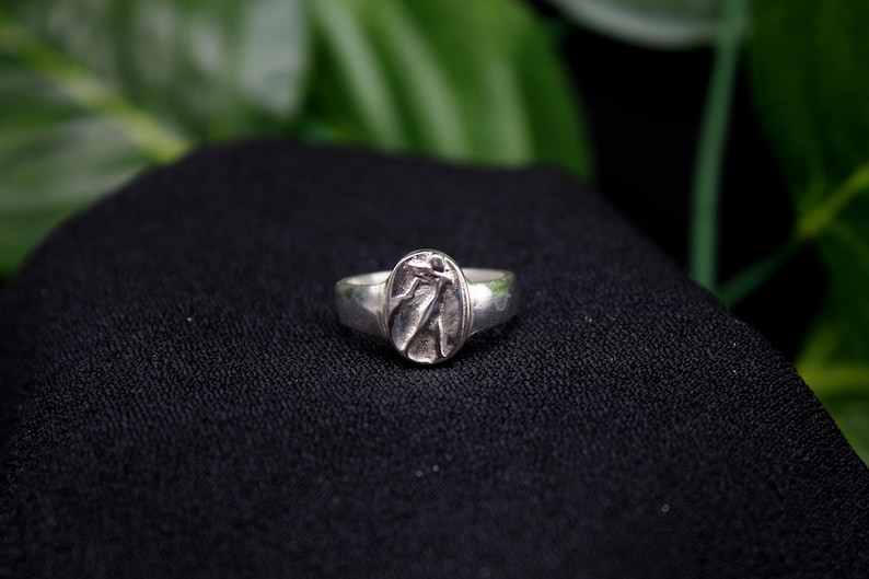 Pu&ograve; includere: Un anello d'argento con un design ovale che presenta un motivo testurizzato e astratto.