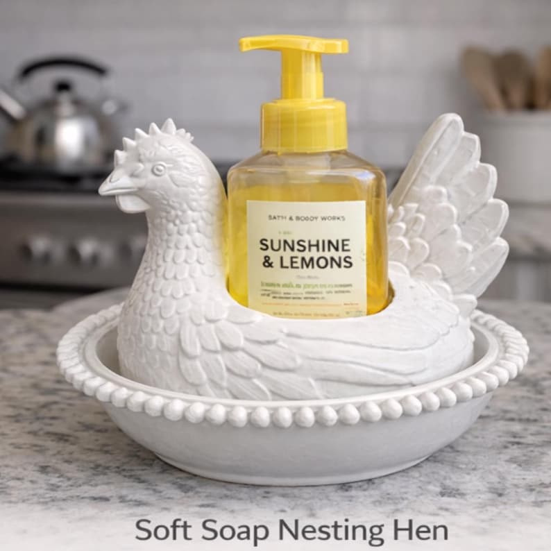 K&ouml;nnte beinhalten: Ein wei&szlig;er Keramik-Seifenspender in Form eines Huhns h&auml;lt eine klare Flasche Fl&uuml;ssigseife mit gelbem Pumpkopf. Auf der Seifenflasche steht "Sunshine & Lemons". Der Spender steht auf einer Arbeitsplatte.