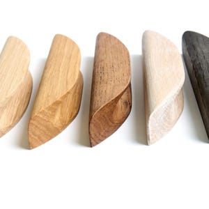 以下が含まれることがあります： 異なる仕上げのウッド製引き出しノブが5つあります。ナチュラル、ライトブラウン、ダークブラウン、ホワイト、ブラック。ノブは、わずかにカーブした三日月形をしています。