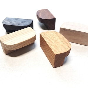 Könnte beinhalten: Fünf Holzknauf für Schränke in verschiedenen Brauntönen. Die Knäufe sind alle halbrund und haben eine glatte, polierte Oberfläche.