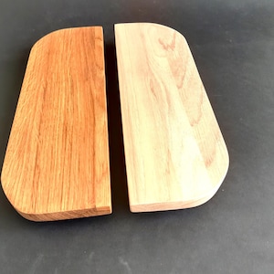 May include: Two wooden cutting boards, one with a natural finish and the other with a darker stain. Both boards are shaped like a rounded rectangle.