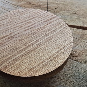 Può includere: Un disco rotondo in legno con una finitura in legno naturale. Il disco è liscio e ha un bordo leggermente arrotondato.