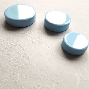 May include: Three light blue round lids of different sizes. The lids are smooth and glossy.