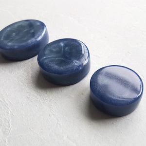 Puede incluir: Tres posavasos redondos de resina azul con un acabado brillante e iridiscente.