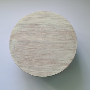 Op de afbeelding: Een rond houten deksel met een lichte houtnerf en een witte afwerking.