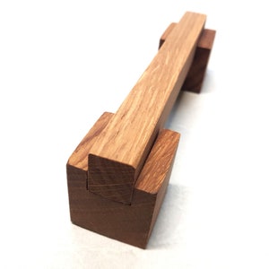 May include: A wooden puzzle with two pieces that fit together. The puzzle is made of light brown wood and has a natural finish.