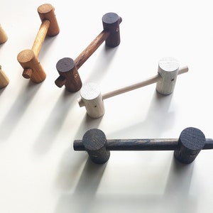 Może przedstawiać: Pięć drewnianych haczyków w różnych kolorach i stylach. Haczyki są wykonane z drewna i mają prosty design. Idealnie nadają się do wieszania płaszczy, czapek lub innych przedmiotów.