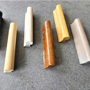 May include: Assortment of six different wooden cabinet pulls in various colors and styles. The pulls are all about 4 inches long and have a curved shape.