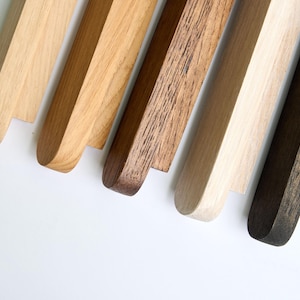 May include: Five wooden samples in different shades of brown, from light to dark. The samples are arranged in a row, with the lightest sample at the top and the darkest sample at the bottom.
