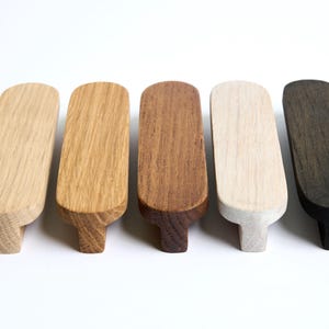 Könnte beinhalten: Fünf Holzknaufgriffe in verschiedenen Holztönen, darunter Natur, Braun, Weiß und Schwarz.