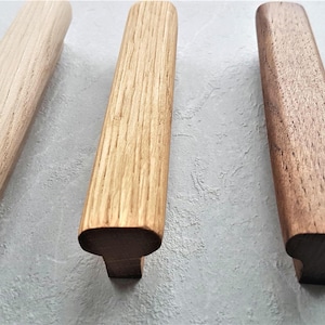 Peut inclure: Trois poignées de tiroir en bois de forme rectangulaire arrondie. Les poignées sont en bois clair, bois moyen et bois foncé.