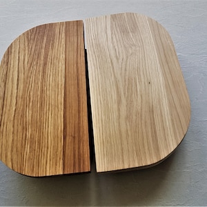 May include: Two wooden chopping boards, one with a light brown finish and the other with a darker brown finish. Both boards have a rounded, slightly curved shape.