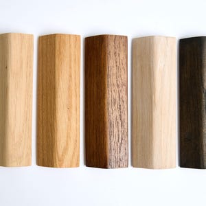 Op de afbeelding: Vijf houtstalen in verschillende tinten bruin, van licht tot donker. De stalen zijn horizontaal gerangschikt, met het lichtste staal links en het donkerste staal rechts.