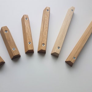 May include: Seven wooden drawer pulls with a triangular shape and a light brown finish. Each pull has two silver screws.