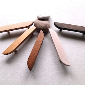 Può includere: Sei tiretti per cassetti in legno in diverse tonalità di marrone, disposti a forma di stella su una superficie bianca.