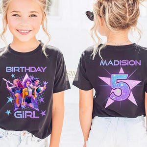 May include: A black t-shirt with a colorful graphic design and the words "BIRTHDAY GIRL" in a purple and blue font. The back of the shirt has the name "MADISION" and the number "5" in a star shape.