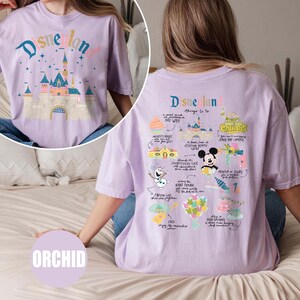 Może przedstawiać: Fioletowy T-shirt z nadrukiem graficznym zamku Disneylandu i tekstem "Disneyland" z przodu. Z tyłu T-shirt ma nadrukowane grafiki atrakcji Disneylandu i tekst "Disneyland rzeczy do zrobienia".