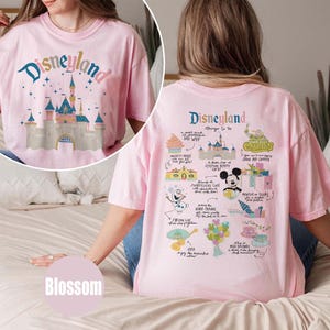 Może przedstawiać: R&oacute;żowa koszulka z grafiką zamku Disneylandu z przodu i listą rzeczy do zrobienia w Disneylandzie z tyłu. Tekst z tyłu brzmi "Disneyland Things to Do".