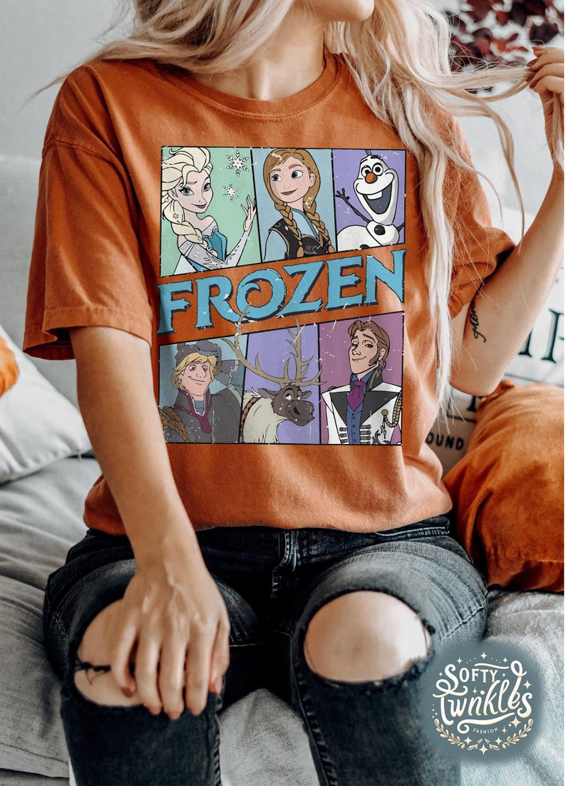 May include: A brown t-shirt with a vintage-style graphic of characters from the movie Frozen. The graphic includes Elsa, Anna, Olaf, Kristoff, Sven, and Hans. The text "FROZEN" is printed in a distressed font.