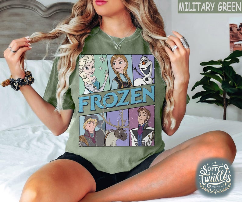 May include: A green t-shirt with a graphic print of characters from the movie Frozen. The characters include Elsa, Anna, Kristoff, Olaf, and Sven. The text "FROZEN" is printed in large letters across the center of the shirt.