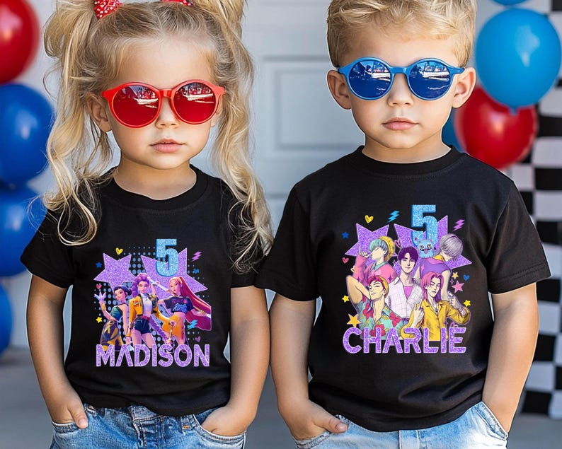 May include: Two children wearing black t-shirts with colorful graphics. The shirts feature a number 5, a star, and cartoon characters. One shirt says "MADISON" and the other says "CHARLIE". Both children are wearing sunglasses.