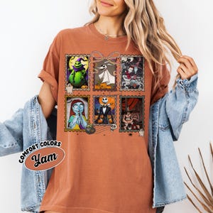 May include: Burnt orange t-shirt featuring six postage stamp-style images of characters from The Nightmare Before Christmas. The shirt has the words "Comfort Colors" and "Yam" printed on it.