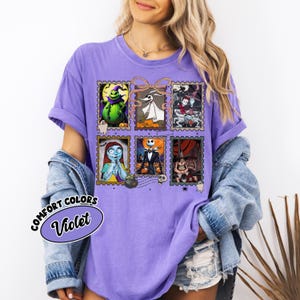 May include: A violet Comfort Colors t-shirt featuring six postage stamp-style images of characters from The Nightmare Before Christmas. The shirt has a relaxed fit and short sleeves. The text "Comfort Colors Violet" is printed on the shirt.