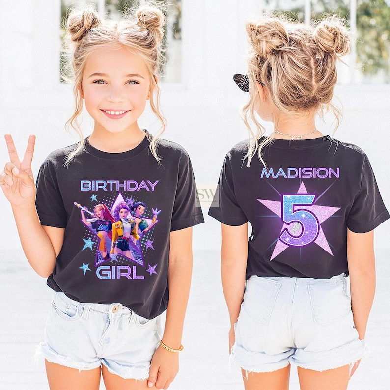 May include: A black t-shirt with a colorful graphic design and the words "BIRTHDAY GIRL" in a purple and blue font. The back of the shirt has the name "MADISION" and the number "5" in a star shape.