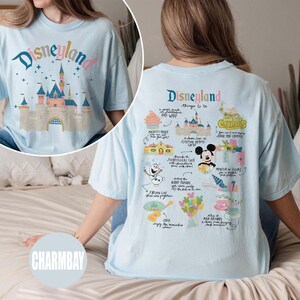 Może przedstawiać: Jasnoniebieska koszulka z nadrukiem graficznym zamku Śpiącej Kr&oacute;lewny z Disneylandu z przodu i listą rzeczy do zrobienia w Disneylandzie z tyłu. Tekst z tyłu zawiera "Disneyland", "Rzeczy do zrobienia", "Dom Myszki Miki", "Rejs po dżungli", "Zamek Śpiącej Kr&oacute;lewny", "Spacer po nawiedzonym domu", "Nocny poch&oacute;d", "Zamarznięte jezioro", "Coco", "Szalona herbata" i "Potwory i sp&oacute;łka. Drzwi".