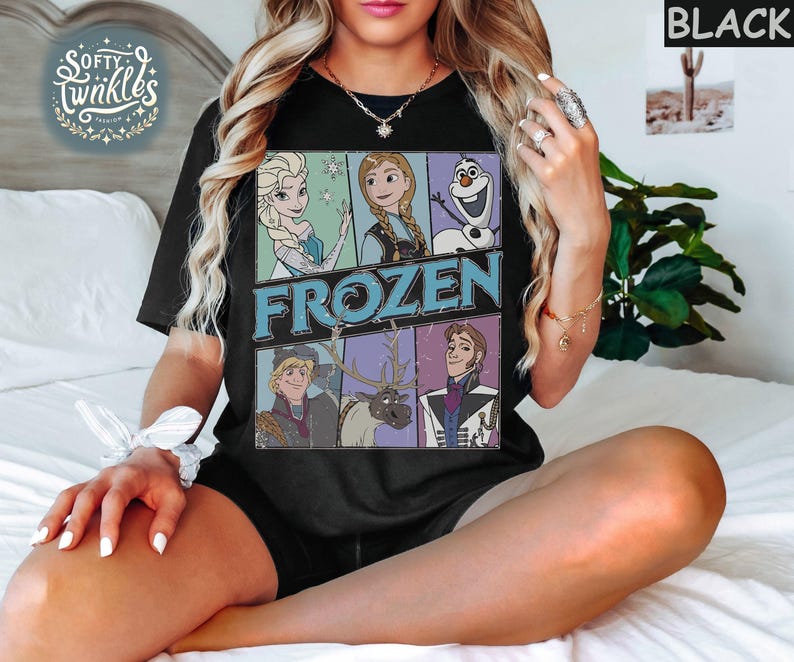May include: Black t-shirt with a vintage-style graphic of characters from the Disney movie Frozen. The graphic features Elsa, Anna, Kristoff, Olaf, and Sven. The text "FROZEN" is printed in large, bold letters.
