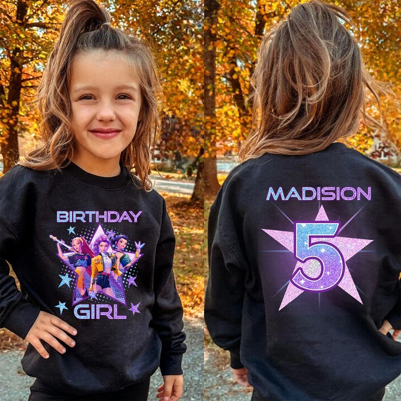 May include: Black sweatshirt with a colorful graphic on the front that says "BIRTHDAY GIRL" and features a cartoon image of three girls. The back of the sweatshirt has the name "MADISION" and the number "5" inside a star.