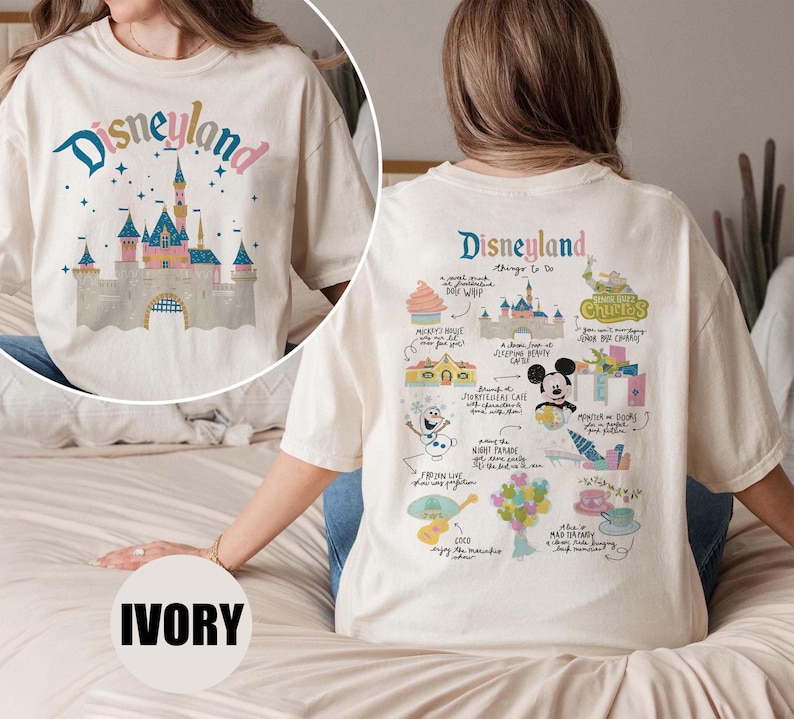 Może przedstawiać: Biały T-shirt z nadrukiem graficznym zamku Śpiącej Kr&oacute;lewny z Disneylandu z przodu i listą rzeczy do zrobienia w Disneylandzie z tyłu. Tekst z tyłu zawiera "Disneyland things to do", "Mickey's House", "Sleeping Beauty Castle", "Churros", "Mad Tea Party", "Frozen", "Coco" i wiele innych.