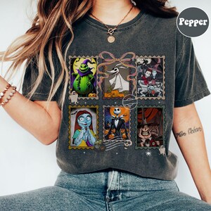 May include: Dark gray t-shirt featuring a collage of six postage stamp-style images of characters from The Nightmare Before Christmas. The images include Jack Skellington, Sally, and Oogie Boogie. The shirt has a vintage, worn look.