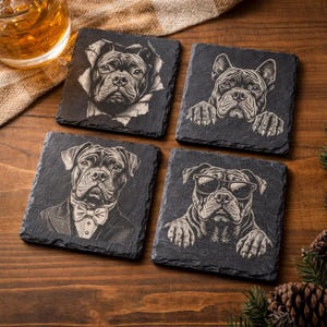 May include: Set of four black slate coasters featuring engraved dog portraits. Each coaster showcases a different dog design: one bursting through a tear, one peeking over a ledge, one in a tuxedo, and one wearing sunglasses.
