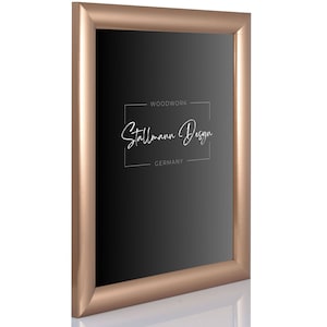 Può includere: Una cornice per foto in oro rosa con un passepartout nero e il testo "Woodwork Stallmann Design GERMANY" stampato sul passepartout.