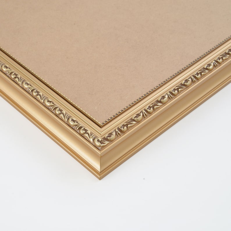 K&ouml;nnte beinhalten: Ein goldener Bilderrahmen mit einem verzierten Design. Der Rahmen ist aus Holz und hat eine glatte Oberfl&auml;che.