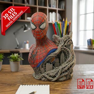 Puede incluir: Un portalápices con forma de busto de Spider-Man rojo, azul y negro con un diseño de paisaje urbano. El portalápices está lleno de lápices y bolígrafos de colores. La imagen también incluye un bloc de notas, un bolígrafo y pequeñas plantas.